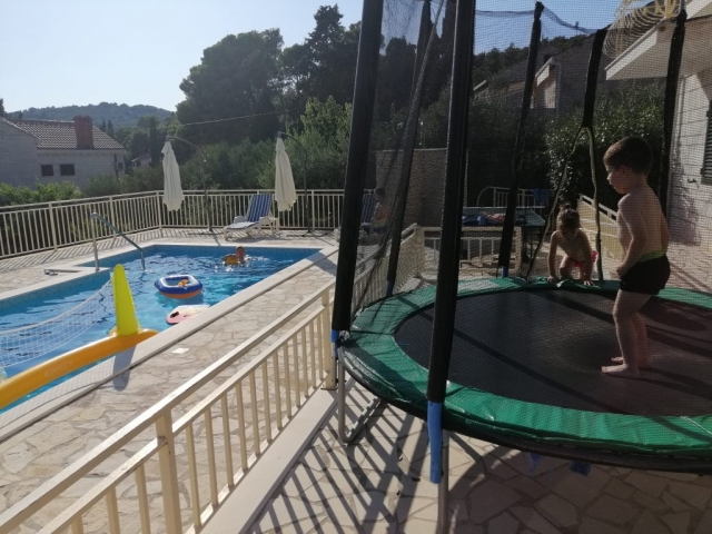 Children playing on the trampoline and in the swimming pool